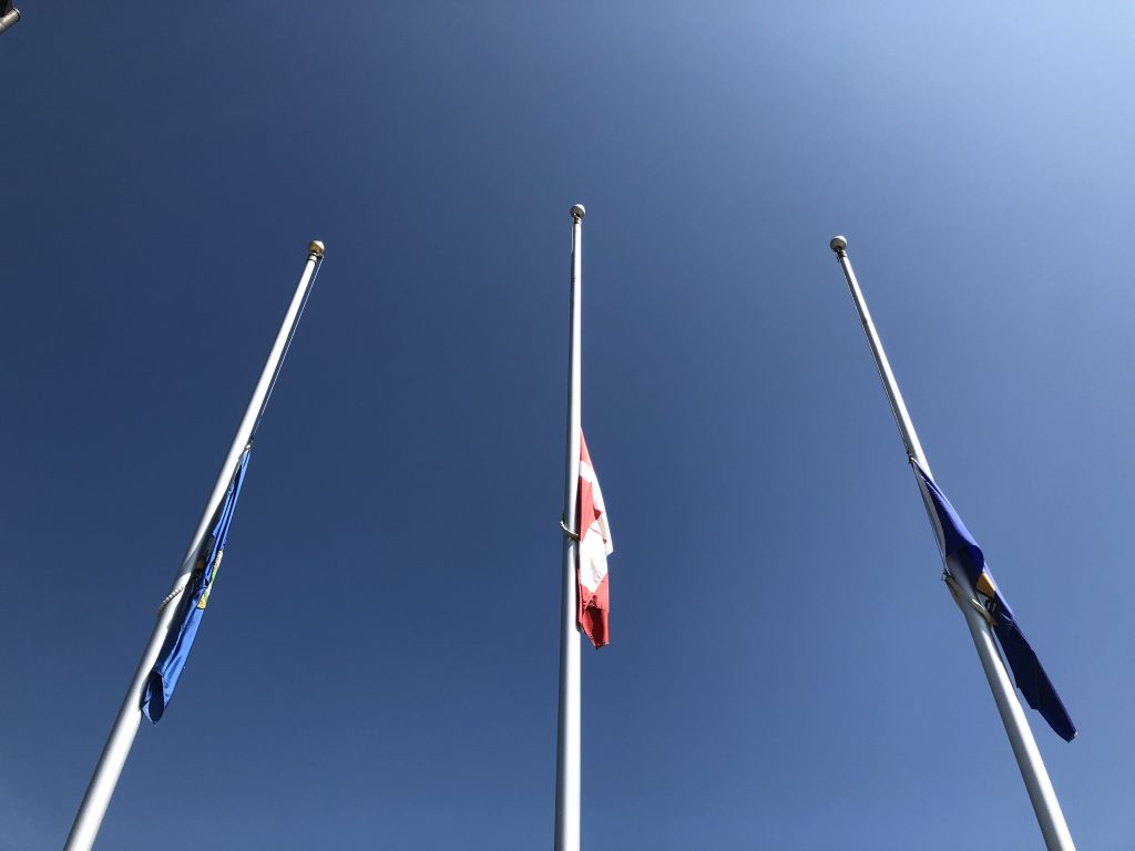 The flags of Canada, Alberta, and Wheatland County flags at half-mast